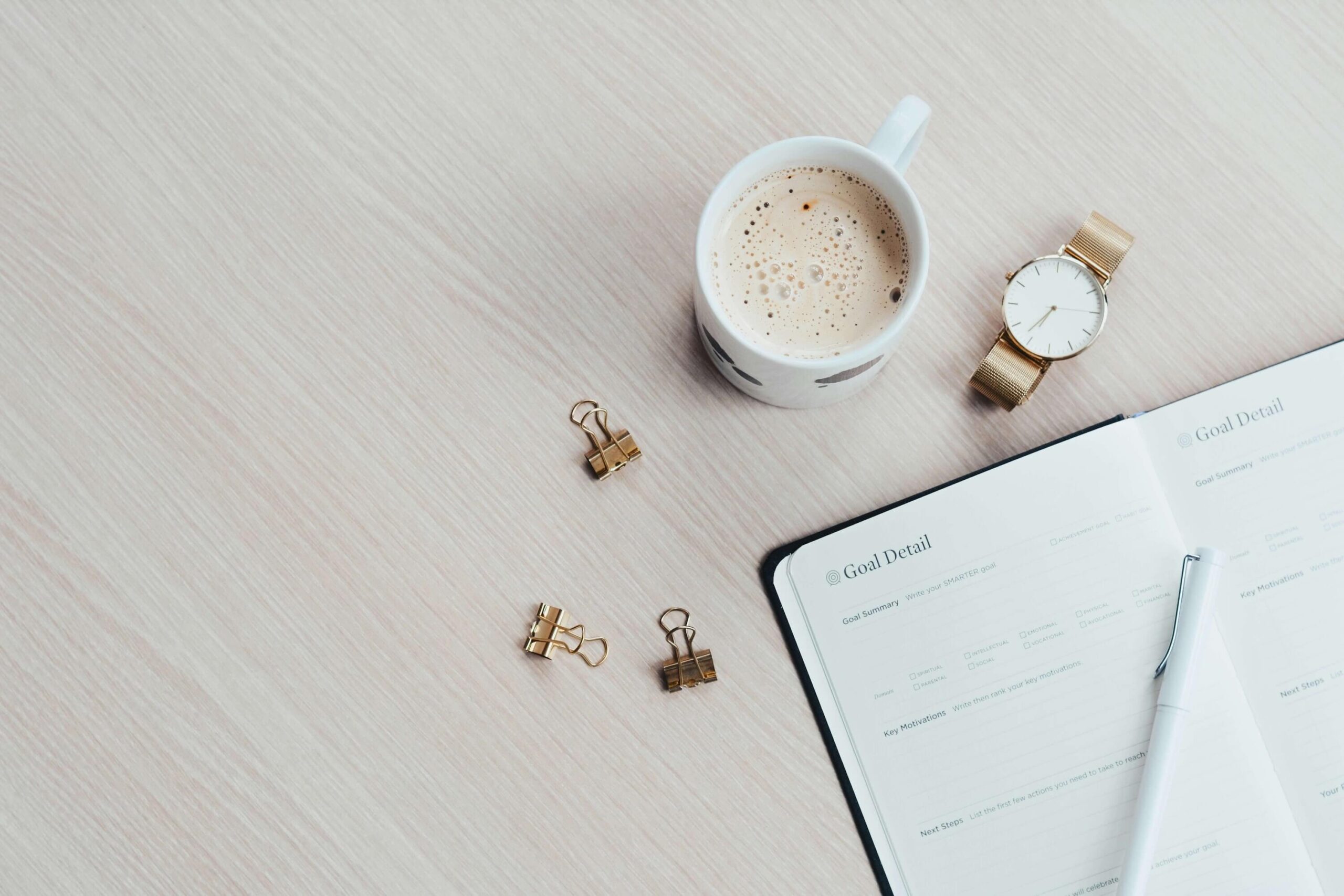 A desk contains coffee, a watch, and a habit tracker.